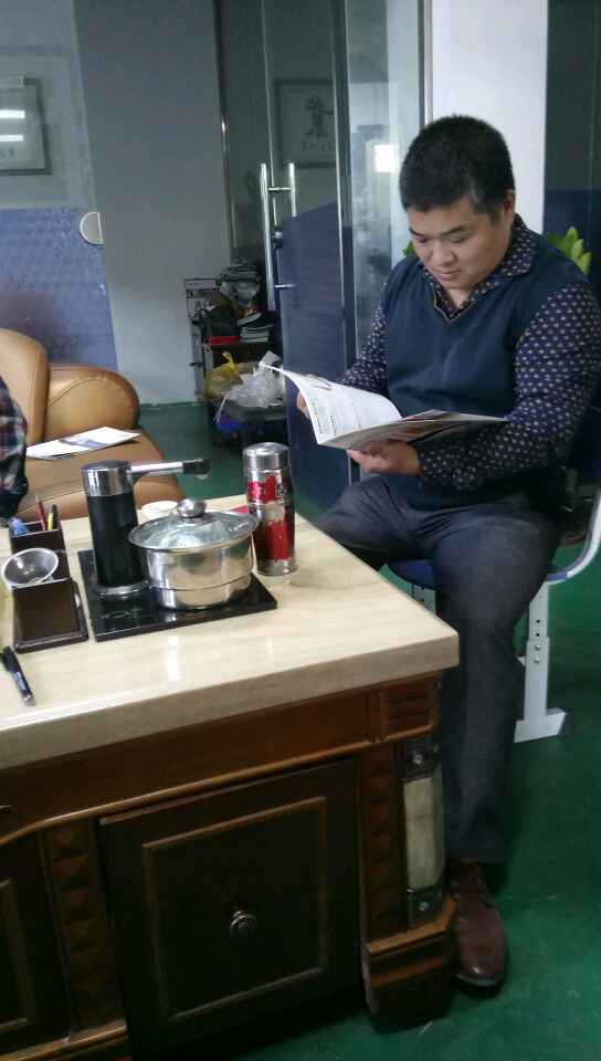 南海陳祥明老板想買凱恩利46車先銑機——在邊聽業務代表講解產品特點優點邊看宣傳書。